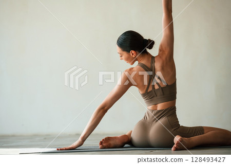 Yoga session. Young woman with slim body type is in fitness clothes in the studio Yoga session. Young woman with slim body type is in fitness clothes in the studio 128493427