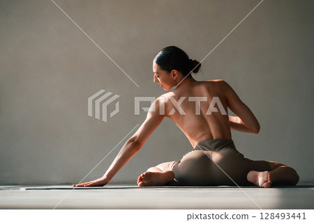 Without bra, sitting on the floor. Young woman with slim body type is in fitness clothes in the studio Without bra, sitting on the floor. Young woman with slim body type is in fitness clothes in the studio 128493441