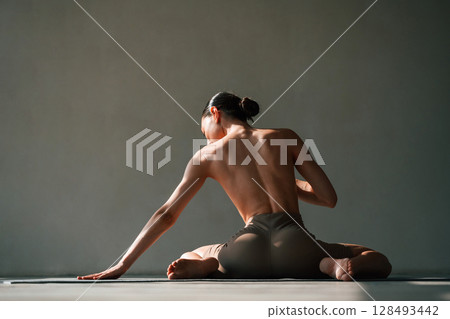 Without bra, sitting on the floor. Young woman with slim body type is in fitness clothes in the studio Without bra, sitting on the floor. Young woman with slim body type is in fitness clothes in the studio 128493442
