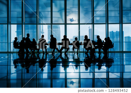A group of business people sitting at a conference table in a modern office with large windows. 128493452