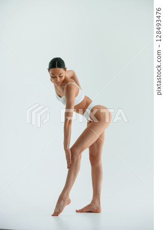 In the studio with white background. Young woman with slim body type is in fitness clothes 128493476