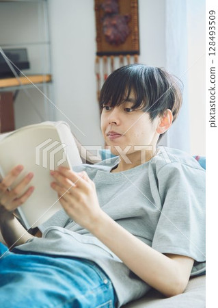 A man reading on a couch 128493509