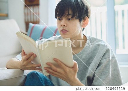 A man reading on a couch 128493519