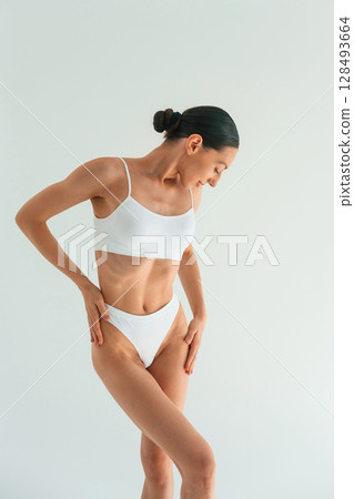 Showing the slim body type. Young woman is in fitness clothes in the studio Showing the slim body type. Young woman is in fitness clothes in the studio 128493664