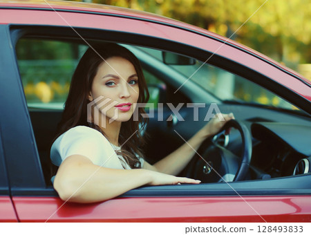 Happy smiling female driver sitting behind the wheel of car 128493833