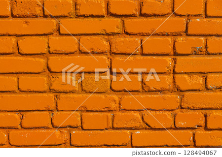 Vibrant orange painted brick wall outdoors during sunny day Vibrant orange painted brick wall outdoors during sunny day 128494067
