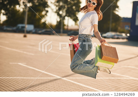 Excited for the sales. Beautiful woman in casual clothes is holding shopping bags, outdoors Excited for the sales. Beautiful woman in casual clothes is holding shopping bags, outdoors 128494269