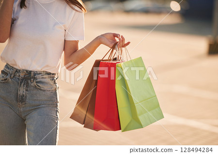 Holding colorful shopping bags. Beautiful woman in casual clothes, outdoors Holding colorful shopping bags. Beautiful woman in casual clothes, outdoors 128494284