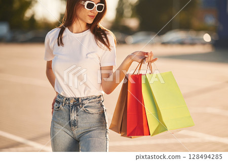Holding colorful shopping bags. Beautiful woman in casual clothes, outdoors Holding colorful shopping bags. Beautiful woman in casual clothes, outdoors 128494285