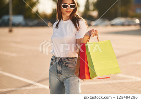 Holding colorful shopping bags. Beautiful woman in casual clothes, outdoors Holding colorful shopping bags. Beautiful woman in casual clothes, outdoors 128494286