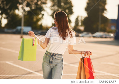 Beautiful woman in casual clothes is holding shopping bags, outdoors Beautiful woman in casual clothes is holding shopping bags, outdoors 128494287