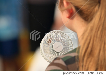 一位手持風扇行走的女士 128494397