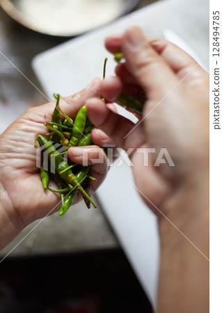 hand holding fresh green chili peppers 128494785
