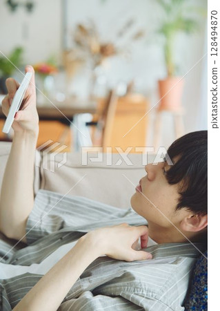 一個男人在客廳看著他的智慧型手機 一個男人在客廳看著他的智慧型手機 128494870