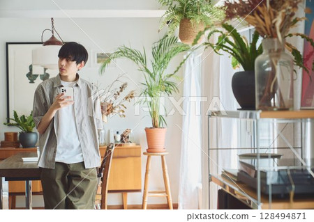 A man looking at his smartphone in the living room 128494871