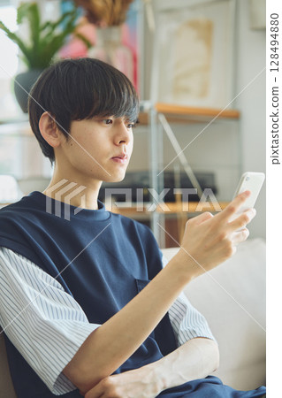 一個男人在客廳看著他的智慧型手機 128494880