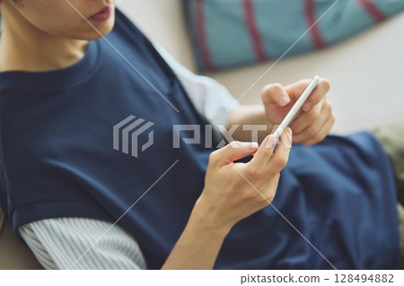 一個男人在客廳看著他的智慧型手機 128494882