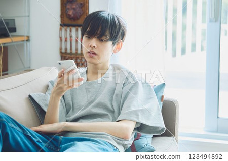 A man looking at his smartphone in the living room 128494892