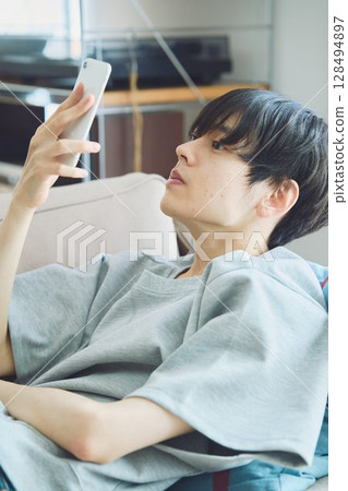 一個男人在客廳看著他的智慧型手機 一個男人在客廳看著他的智慧型手機 128494897