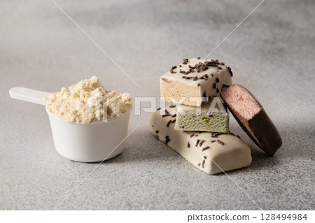 Protein bars and scoop of powder on gray background. Close up. 128494984
