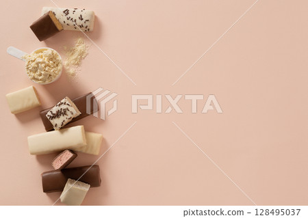 Protein bars with various coatings and sprinkles scoop of protein powder on pink background. Fitness nutrition. View from above 128495037