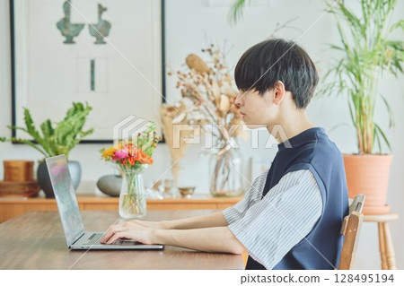 Man using a computer in the dining room 128495194