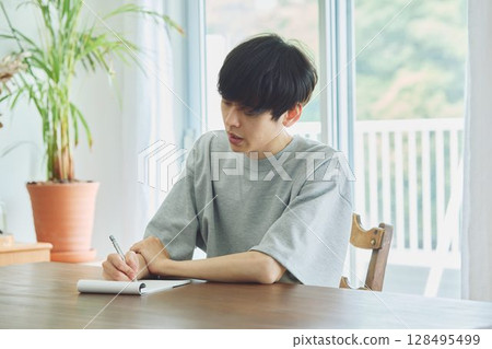 Man taking notes in dining room Man taking notes in dining room 128495499