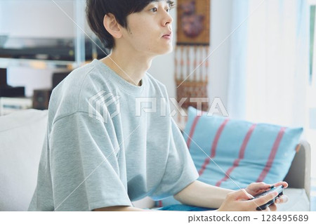 Man playing games in the living room 128495689