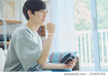 Man playing games in the living room 128495702