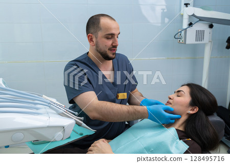 A Dentist Checks a Patient's Jaw and Oral Health in a Modern Dental Clinic Setting with State-of-the-Art Equipment and Comfort for the Patient During a Routine Checkup 128495716