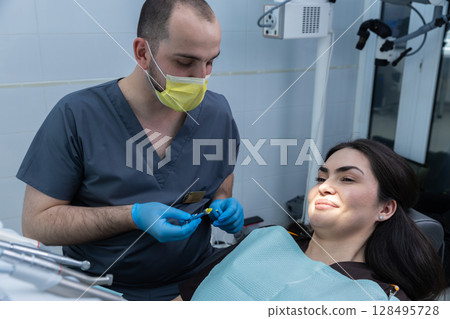 A Dentist Preparing for a Procedure While Attending to a Patient in a Bright and Modern Dental Clinic Environment, Emphasizing Professional Care and Comfort 128495728