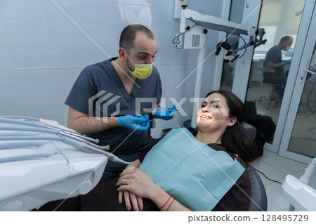 A Dentist Interacts with a Patient in a Modern Clinic Setting, Ensuring Comfort and Care During Dental Procedure, Highlighting the Importance of Oral Health and Patient Experience 128495729