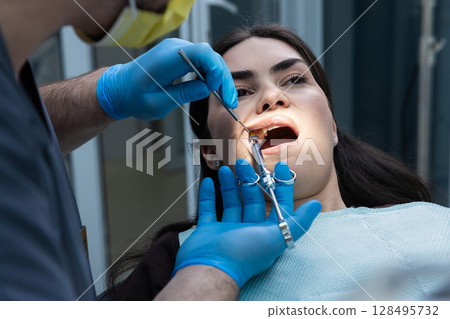 A close-up view of a dental procedure where a healthcare professional is examining a patient s mouth with tools, showcasing the importance of oral health and routine check-ups. 128495732