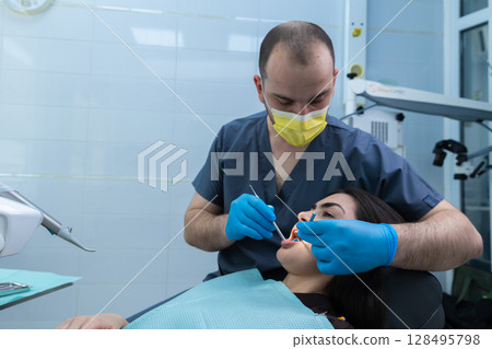 Professional Dentist Providing Dental Care During Oral Procedure with Patient in Dental Chair at Modern Clinic, Emphasizing Importance of Hygiene and Comfort in Dentistry Environment 128495798