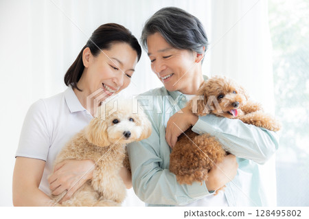 一對中年夫婦在客廳和他們的狗一起玩耍 128495802