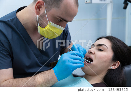 Dental Check-Up: Dentist Using Instruments to Examine a Patient's Teeth and Gums in a Modern Clinic 128495825