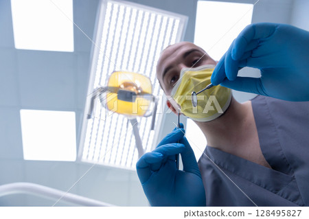 Professional Dentist Preparing for Examination with Dental Tools in Modern Clinic Under Bright Lighting, Ensuring Safe and Clean Environment for Patients' Dental Health Needs 128495827