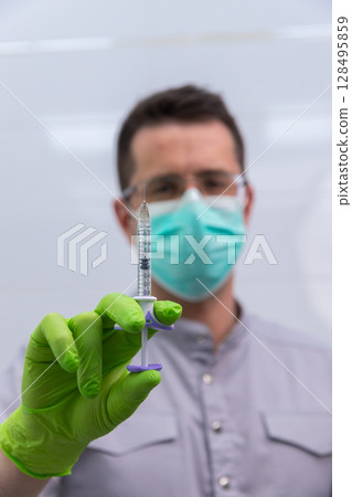 Healthcare Professional Holding a Syringe in a Clinical Setting Highlighting the Importance of Safety and Hygiene Practices in Medical Procedures and Vaccination 128495859
