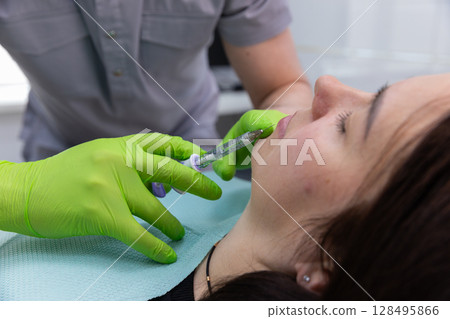 A Close-Up of a Cosmetic Procedure: Injecting Filler into Lips with Precision and Care by a Skilled Professional in a Modern Medical Setting 128495866