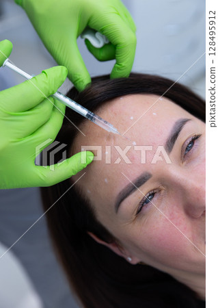 A Professional Aesthetician Administering Botox Injections on a Patient's Forehead for a Smooth, Youthful Appearance in a Modern Clinic Setting A Professional Aesthetician Administering Botox Injections on a Patient's Forehead for a Smooth, Youthful Appearance in a Modern Clinic Setting 128495912