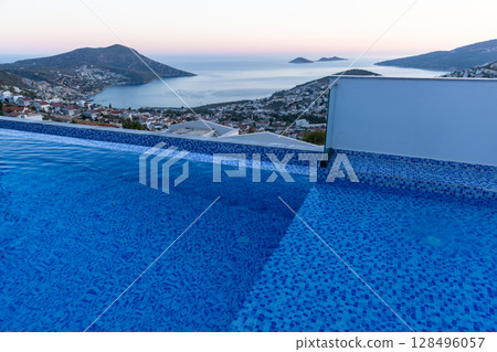 Serene infinity pool with a tranquil sea view of a coastal town Serene infinity pool with a tranquil sea view of a coastal town 128496057