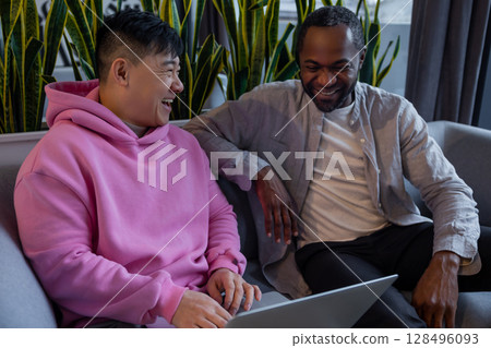 Smiling diverse team members working together on computer in casual office environment 128496093
