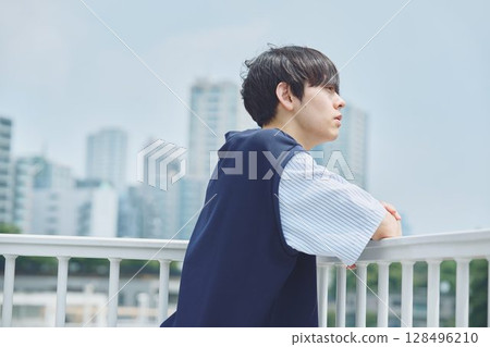 Man standing on balcony of apartment 128496210