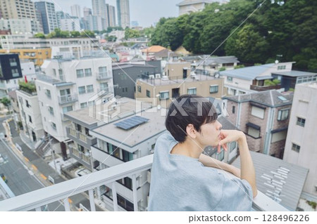Man standing on balcony of apartment Man standing on balcony of apartment 128496226