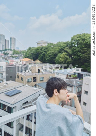 Man standing on balcony of apartment Man standing on balcony of apartment 128496228