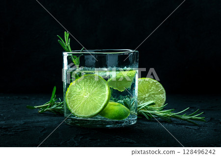 Gin tonic glass, side view with rosemary and lime. Fresh summer drink 128496242