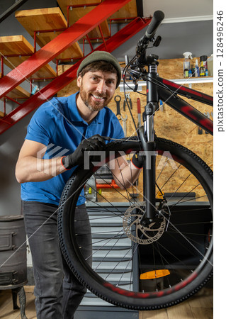 Experienced male adjusting bicycle expertly in tidy workshop 128496246