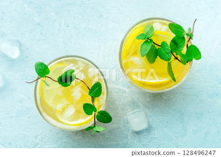 Glasses of lemonade, a mocktail with lemon juice, on a blue background Glasses of lemonade, a mocktail with lemon juice, on a blue background 128496247