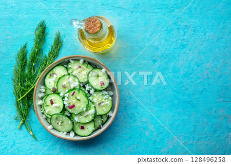 Cucumber salad with olive oil, dill, red onion, and Feta cheese, on blue 128496258