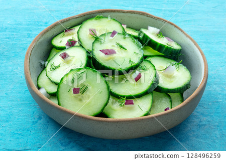 Cucumber salad with olive oil, dill, and red onion, on a blue background 128496259